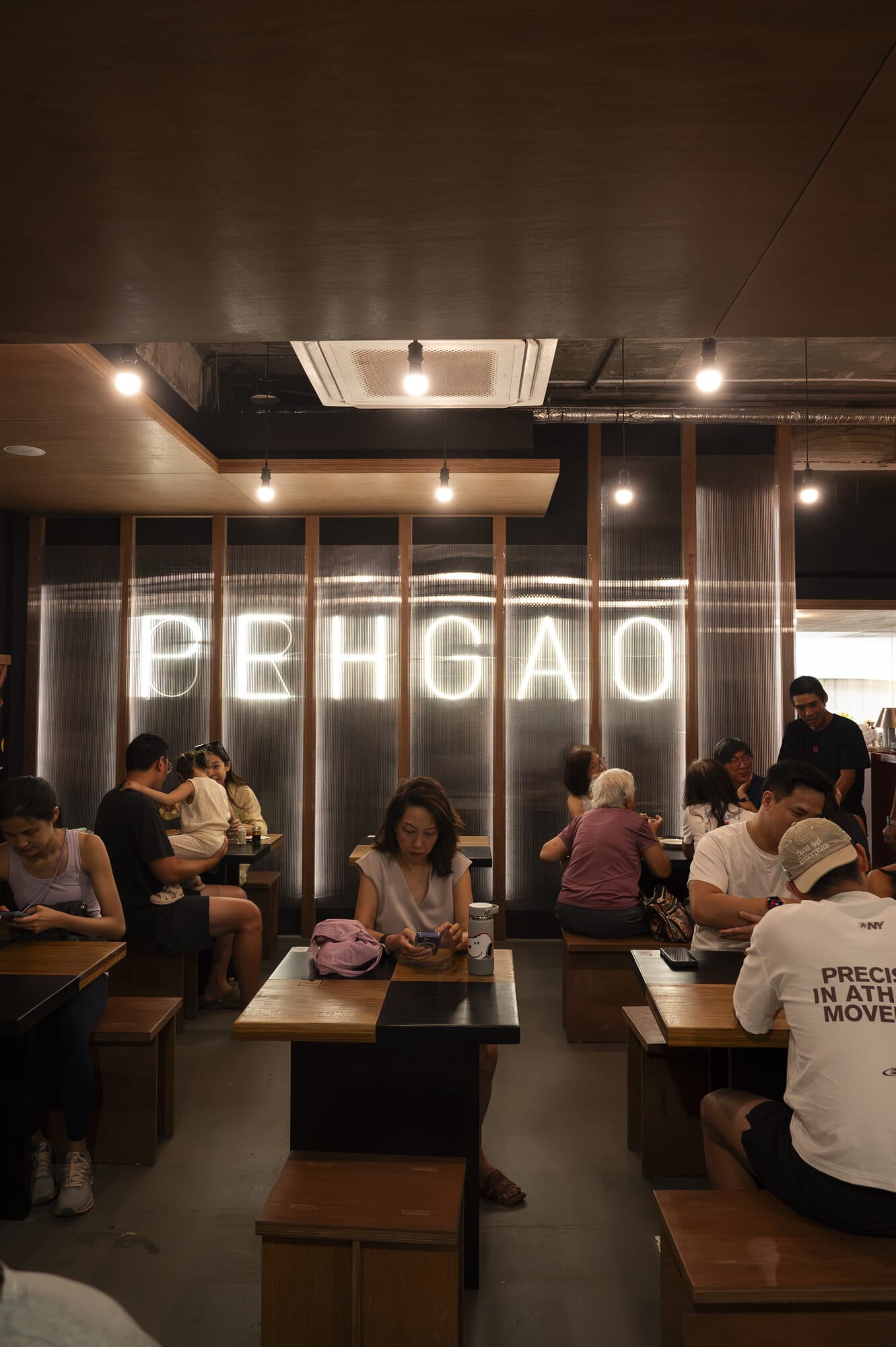 Diners seated at timber tables in the Peh Gao Coffeeshop dining room, beneath an illuminated PEHGAO sign