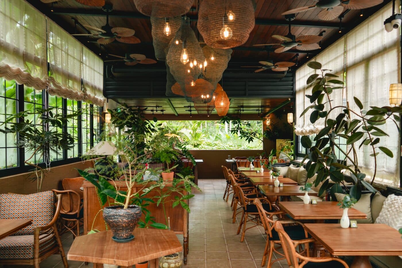 Dining room at Tembusu with hanging glass pendant lights, plants and rattan seating