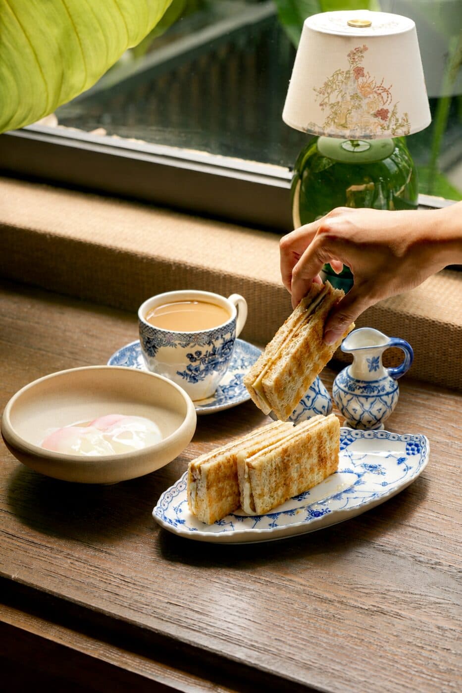 Kaya toast fingers with coffee and a soft-boiled egg on a timber table at Tembusu