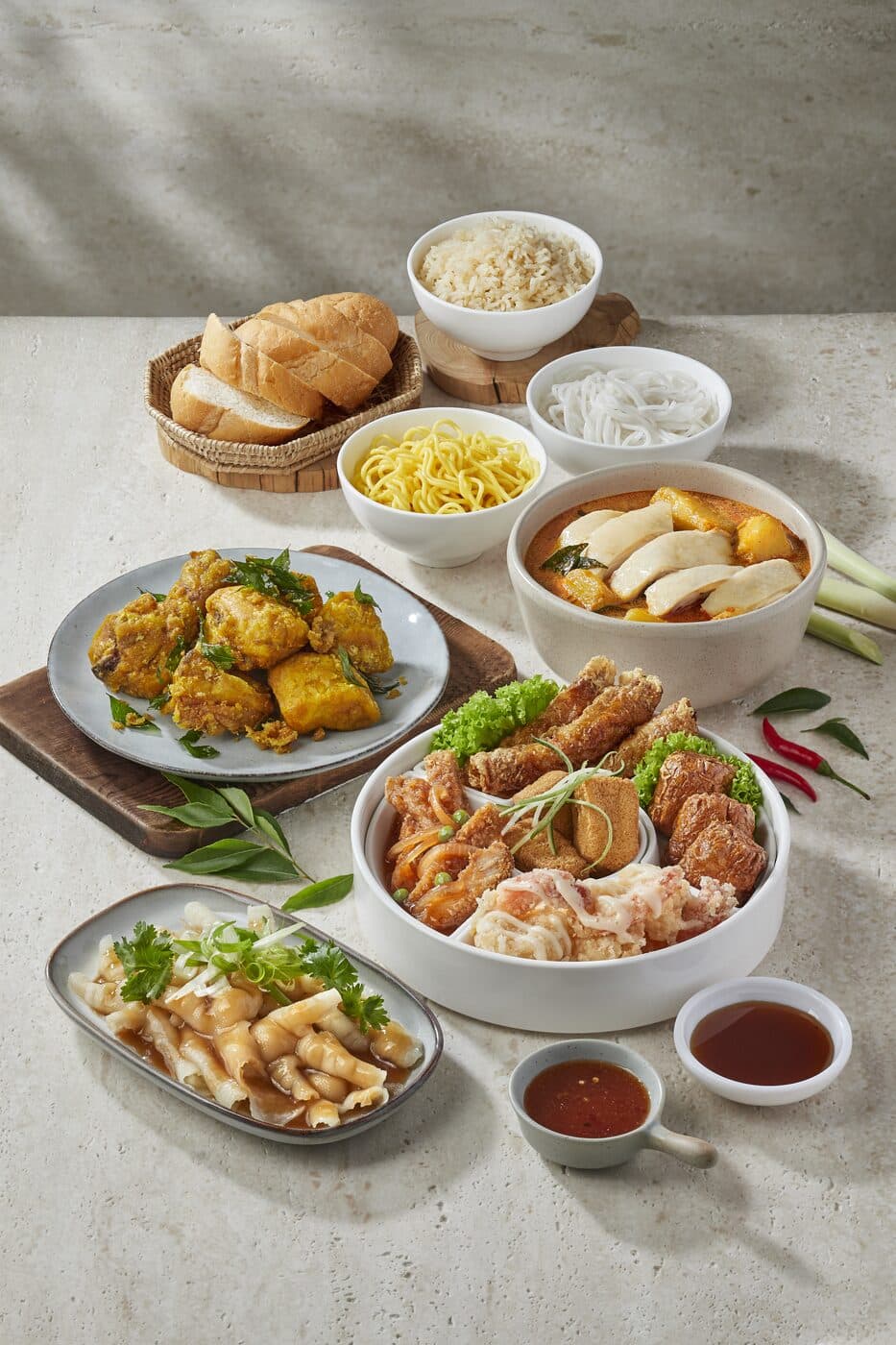Spread of chicken rice with fried side dishes, soup and a basket of buns