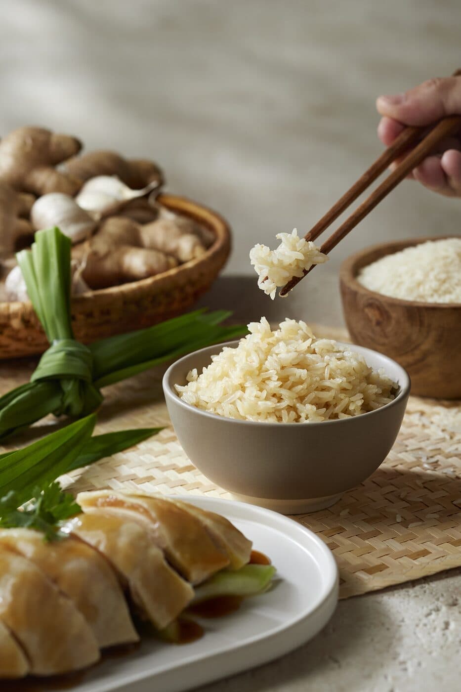Bowl of chicken rice with pandan, ginger and garlic alongside a plate of poached chicken