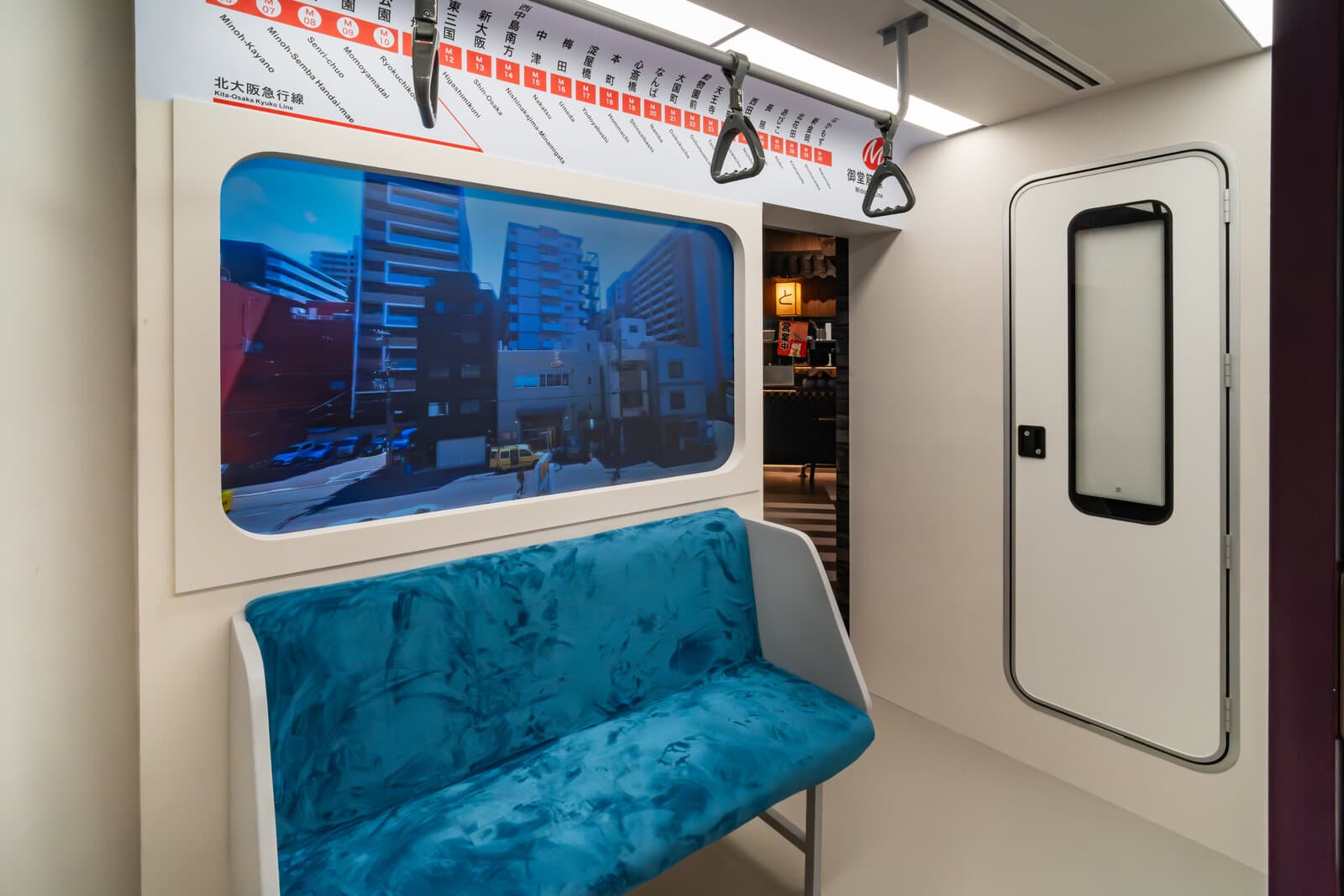 A booth at Tonkatsu Daiki built to look like the inside of a Japanese train carriage, with a turquoise bench seat, hanging grab handles, a route map above the window and a simulated street view through the window