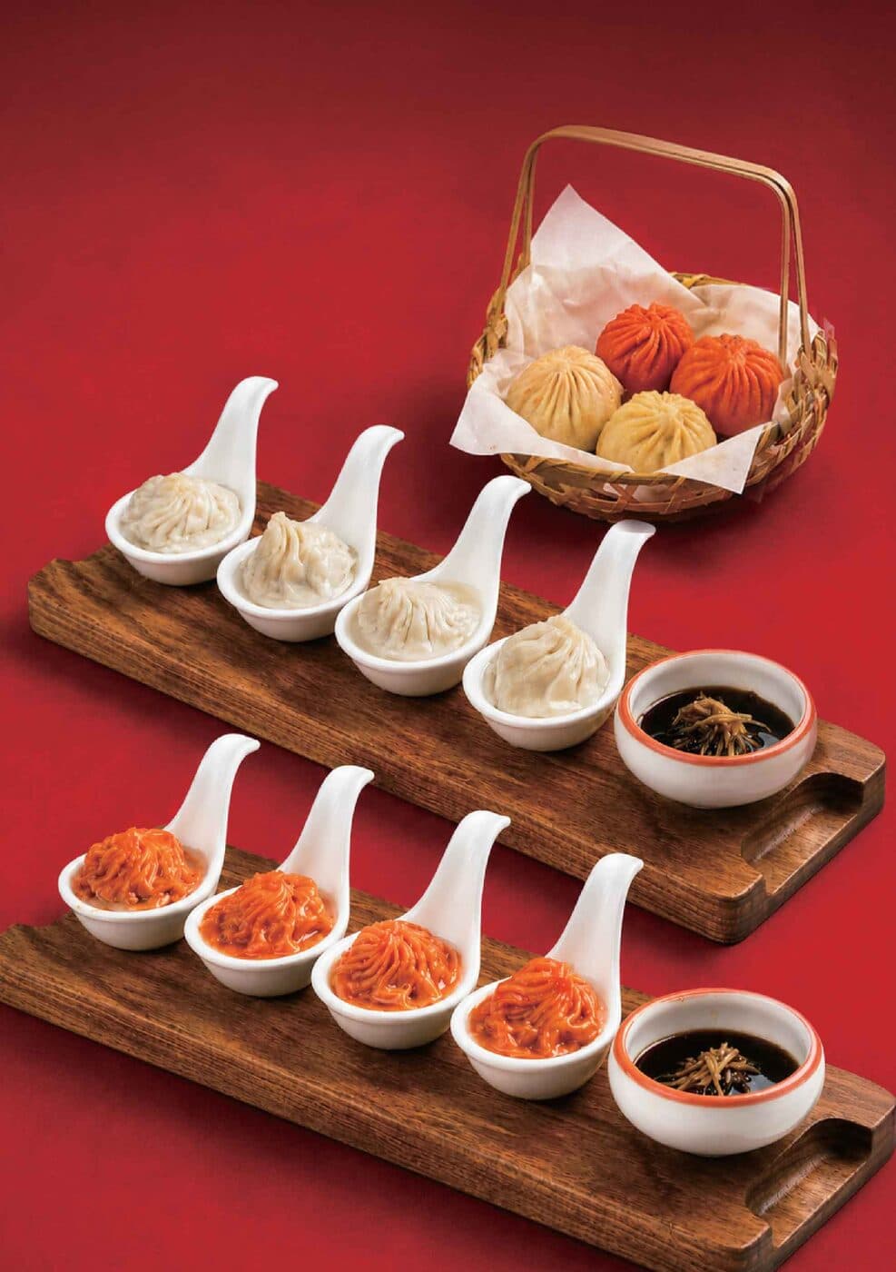 Wooden board of steamed dumplings with small dishes of chilli and dipping sauces