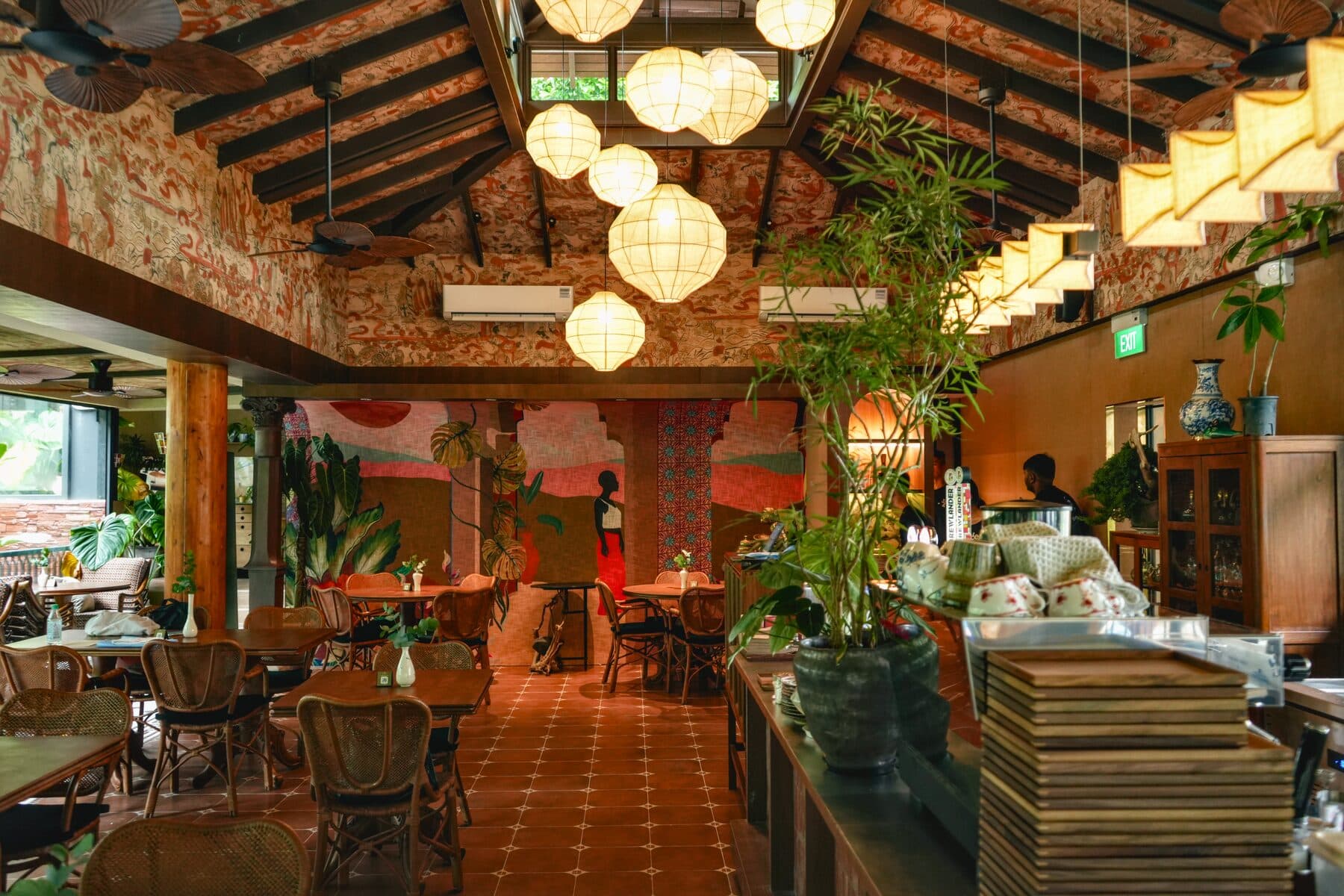 Main dining hall at Tembusu in the Ginger Garden of the Singapore Botanic Gardens, with illustrated walls, timber columns and woven pendant lights