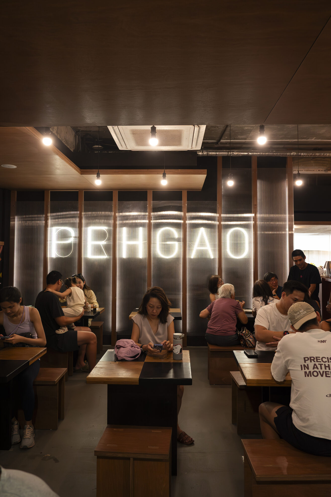 Diners seated at timber tables in the Peh Gao Coffeeshop dining room, beneath an illuminated PEHGAO sign
